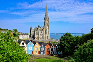Colorful row houses with towering cathedral in background in the port town of Cobh, County Cork.